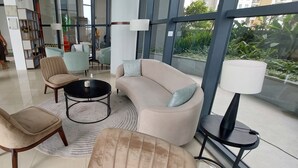 A modern lounge area with comfortable seating, a coffee table, and a large window offering a view of the outdoors. - Nine Peaks Summit TriZen  (Colombo)