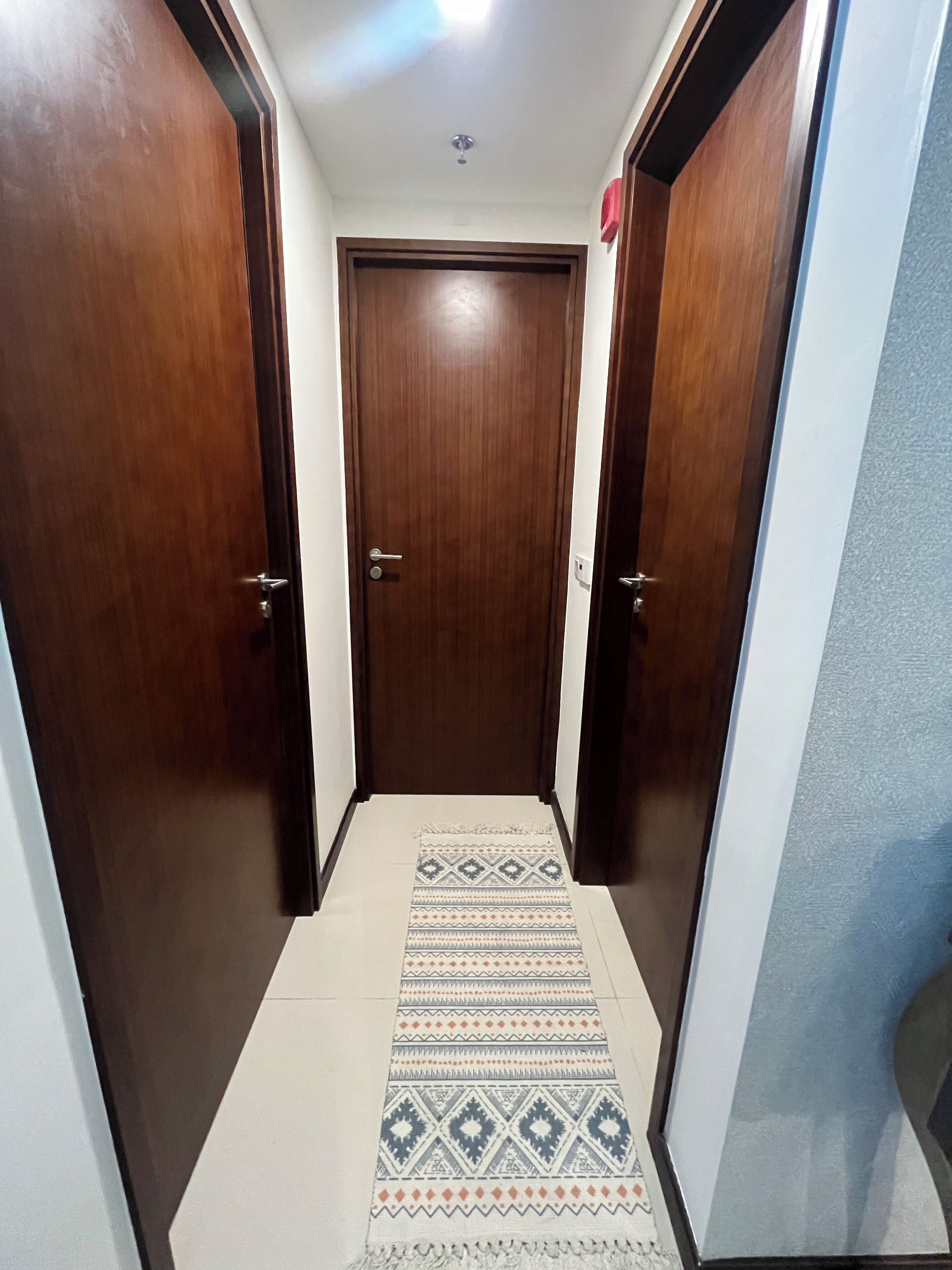 A hallway with wooden doors and a patterned rug.