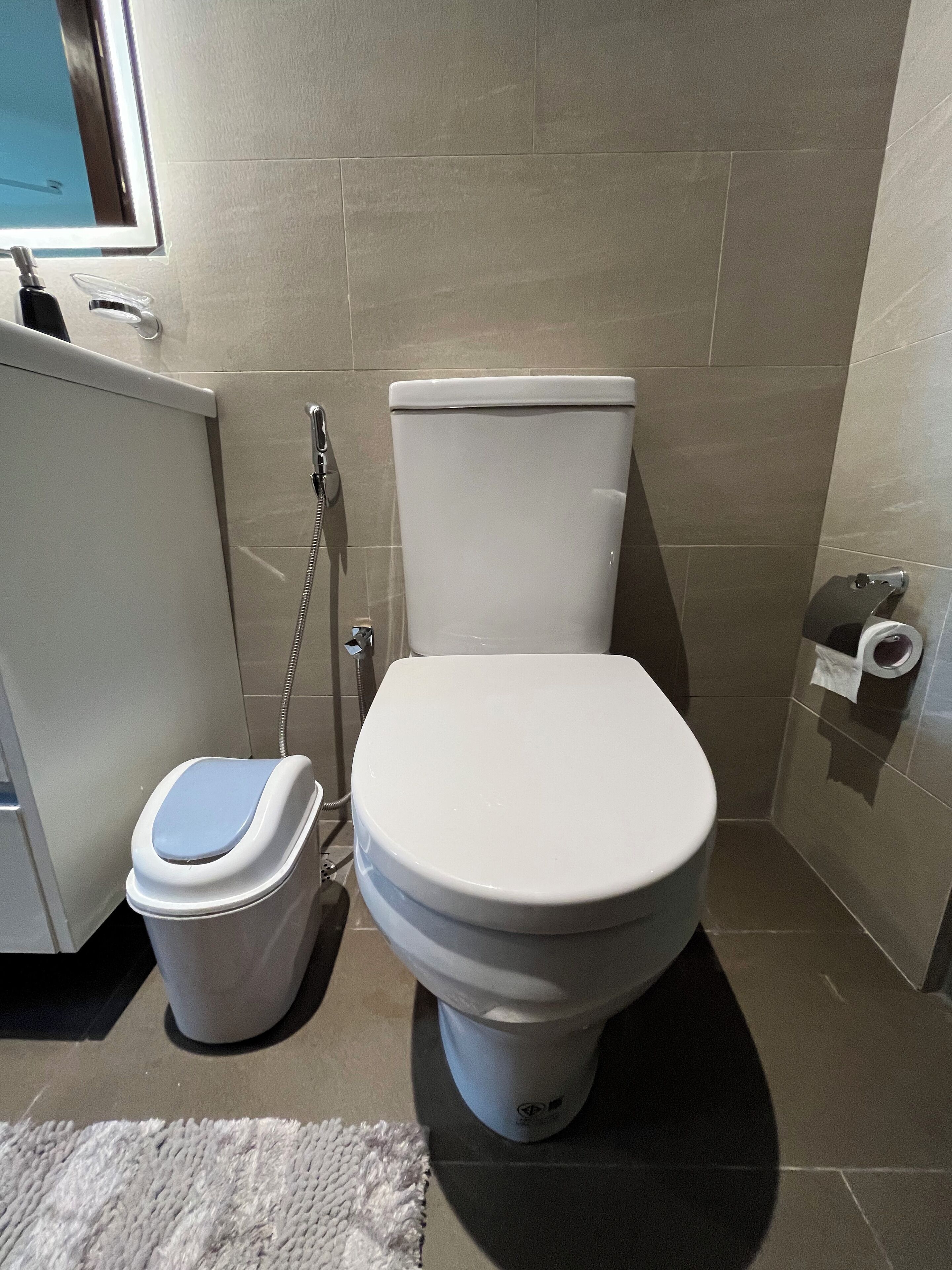 A bathroom with a toilet, bidet, and a small trash bin.