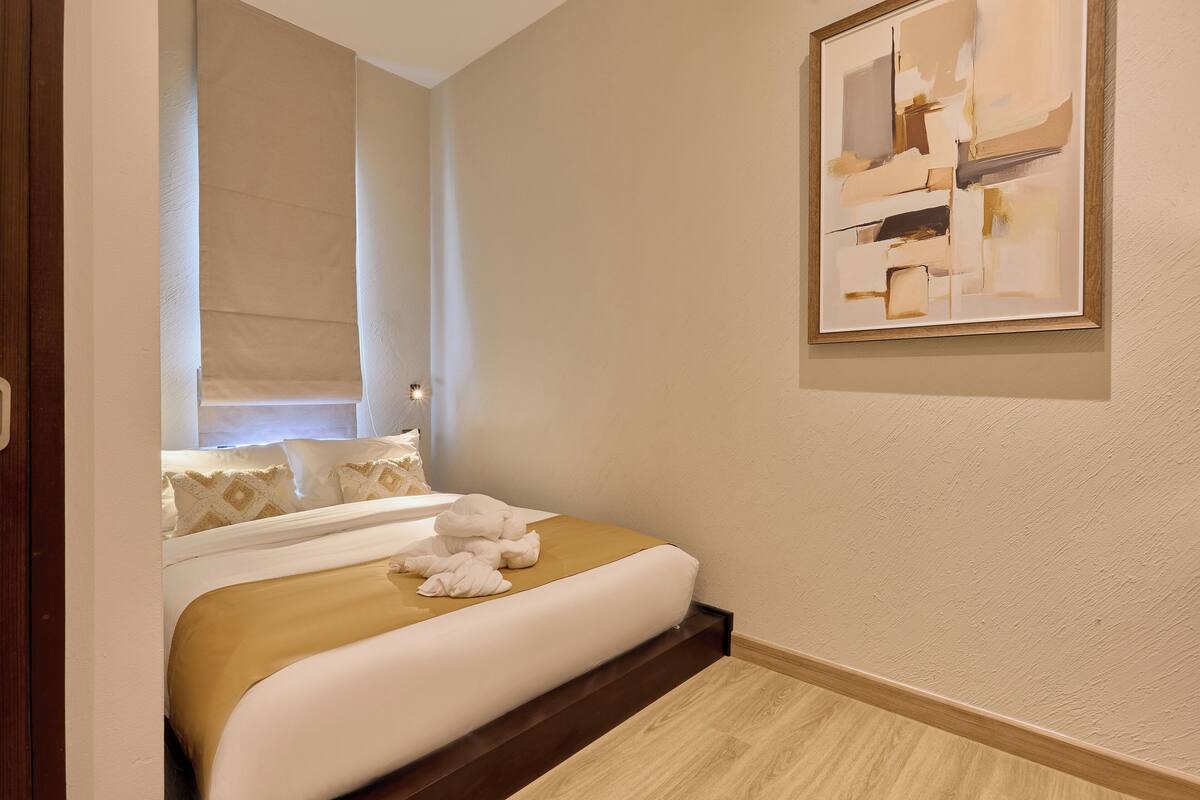 Una habitación de hotel con cama, un cuadro en la pared y suelo de madera.