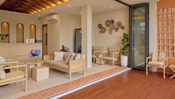 Un moderno vestíbulo de hotel con techo de madera, mostrador de recepción, sofá y varias sillas.