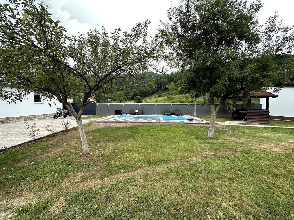 A backyard with a swimming pool, a covered seating area, and a small building.