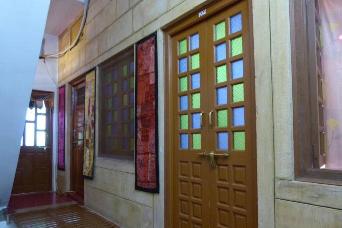A hallway with wooden doors, a red carpet, and a window with a curtain.