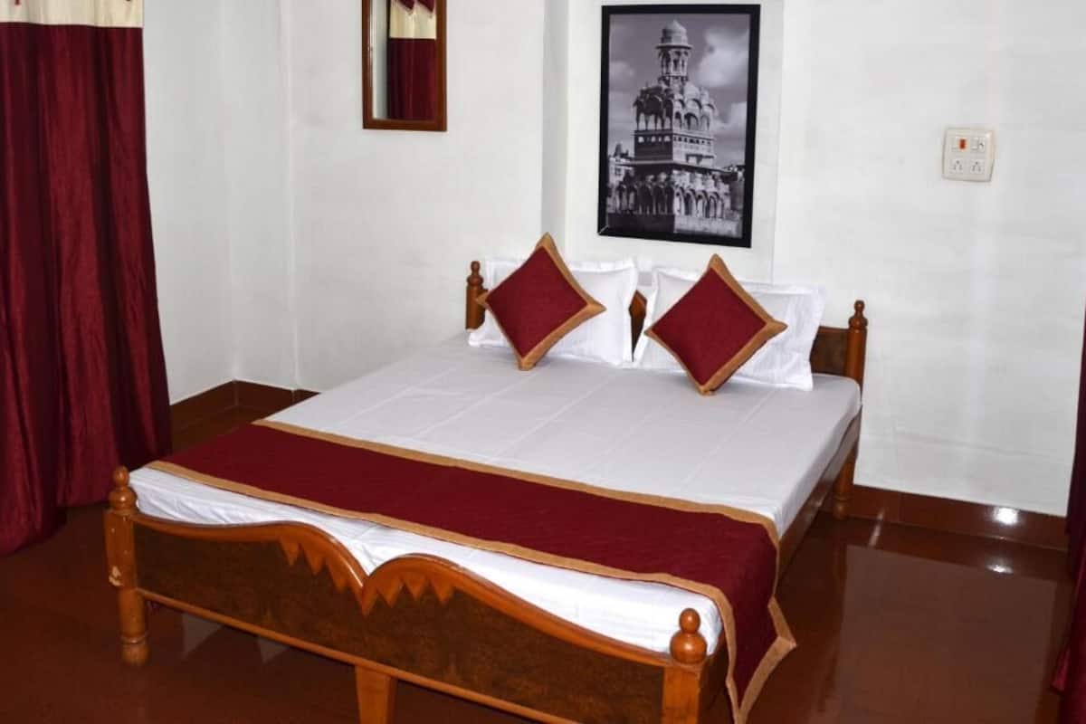 A neatly made bed with a wooden headboard, white bedding, and red accents.