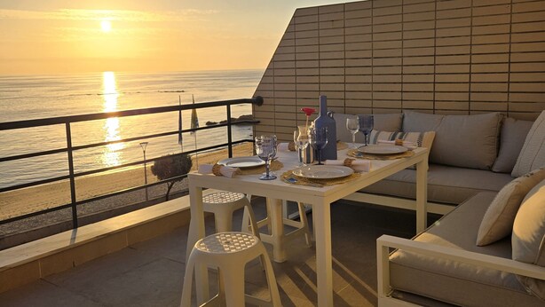 A terrace with a table set for two, overlooking a sunset over the sea. - Azulmaris - Directly on the beach | Terrace & sea view (Vila do Conde)
