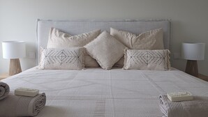 A neatly made bed with a textured white bedspread, two bedside lamps, and two rolled towels on the bed. - Azulmaris - Directly on the beach | Terrace & sea view (Vila do Conde)