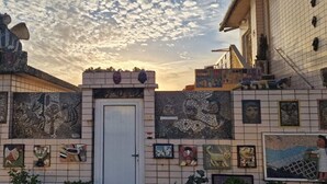 A building with a tiled facade featuring mosaic art and a door. - Azulmaris - Directly on the beach | Terrace & sea view (Vila do Conde)