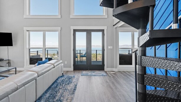 Een ruime woonkamer met een groot raam, een bank en uitzicht op zee.
