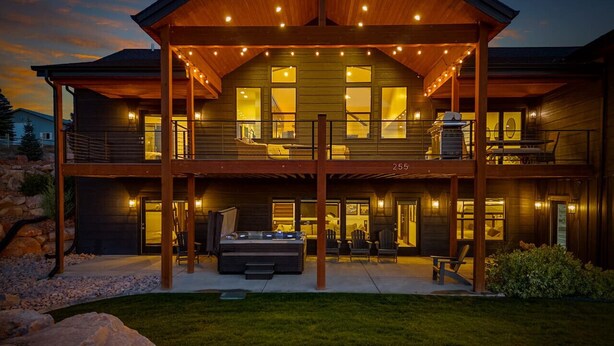Une maison moderne à deux étages, dotée d’un patio couvert, de grandes fenêtres et d’un barbecue.