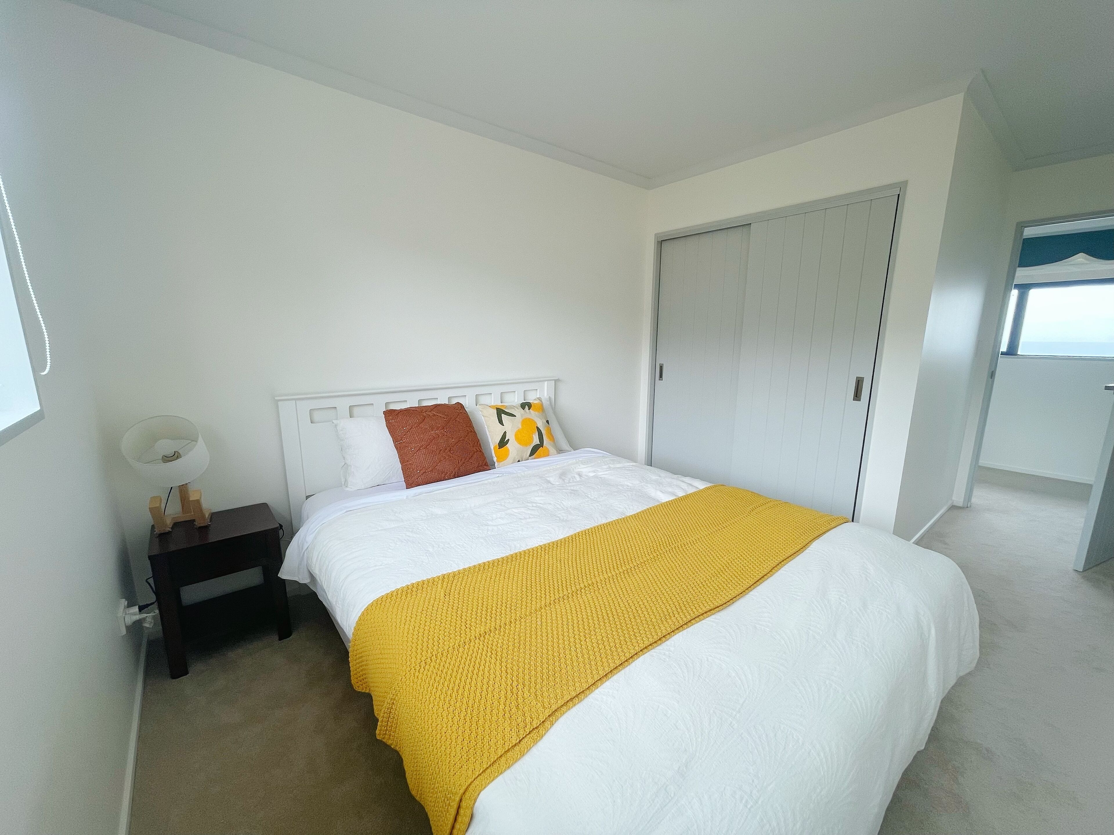 Un dormitorio con cama, mesita de noche, armario y ventana.