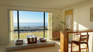 Una habitación moderna con un amplio ventanal que ofrece vistas a la ciudad, una mesa de madera y una zona de estar acogedora.