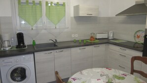 Eine kleine Küche mit Waschmaschine, Kaffeemaschine und Toaster.