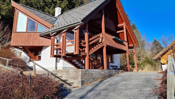 A modern wooden house with a steep roof, a stone foundation, and a wooden staircase leading to a balcony. - House in Bad Kleinkirchheim by Ski Slope (Bad Kleinkirchheim)