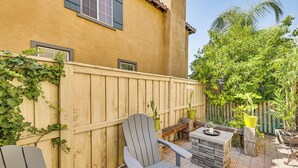 A patio with two Adirondack chairs, a small table, and a stone fireplace. - Extended-Stay Suite Near I-15 in Lake Elsinore! (Lake Elsinore)