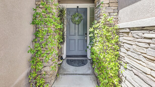 A stone-clad entrance with a gray door, a wreath, and a black doormat. - Extended-Stay Suite Near I-15 in Lake Elsinore! (Lake Elsinore)