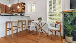 Una cocina con armarios de madera, una mesa redonda de cristal y dos taburetes de madera.