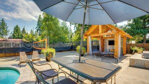 Ein überdachter Patio-Bereich mit Pool, Gartenmöbeln und einer Holz-Pergola.