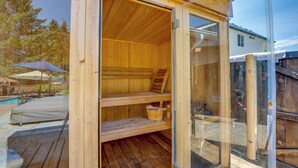 Eine Holzsauna mit Glastüren, Holzbänken und einem kleinen Holztisch.