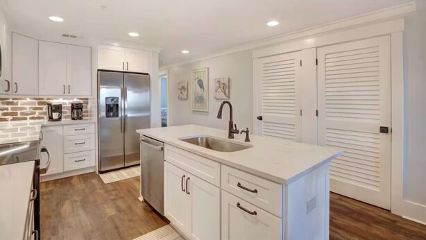 A modern kitchen with white cabinetry, stainless steel appliances, and a central island with a sink. - Ocean Pearl= pool,  beachfront, elevator (Tybee Island)