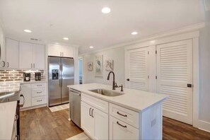 Una cocina moderna con armarios blancos, electrodomésticos de acero inoxidable y una isla central con un lavamanos.