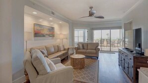 A spacious living room with a sofa, armchairs, a coffee table, and a television. - Ocean Pearl= pool,  beachfront, elevator (Tybee Island)