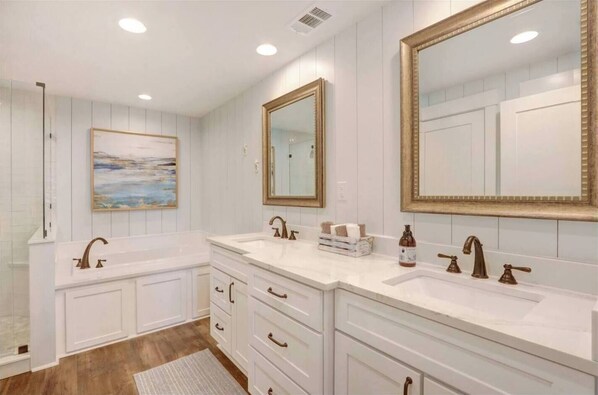 Un baño con dos lavamanos, muebles de color blanco, un espejo grande y un cuadro en la pared.