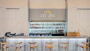 A bar area with a counter, bar stools, and a variety of bottles. - Yevlakh City Hotel (Yevlakh)