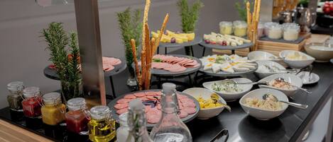 A buffet with various food items, condiments, and small potted plants.