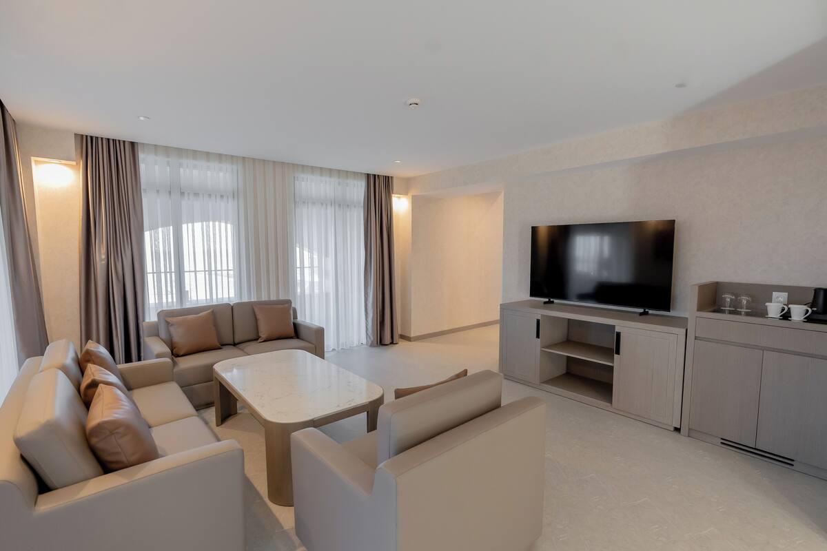 Een moderne woonkamer met een zithoek, een salontafel, een flatscreen televisie en een kast.