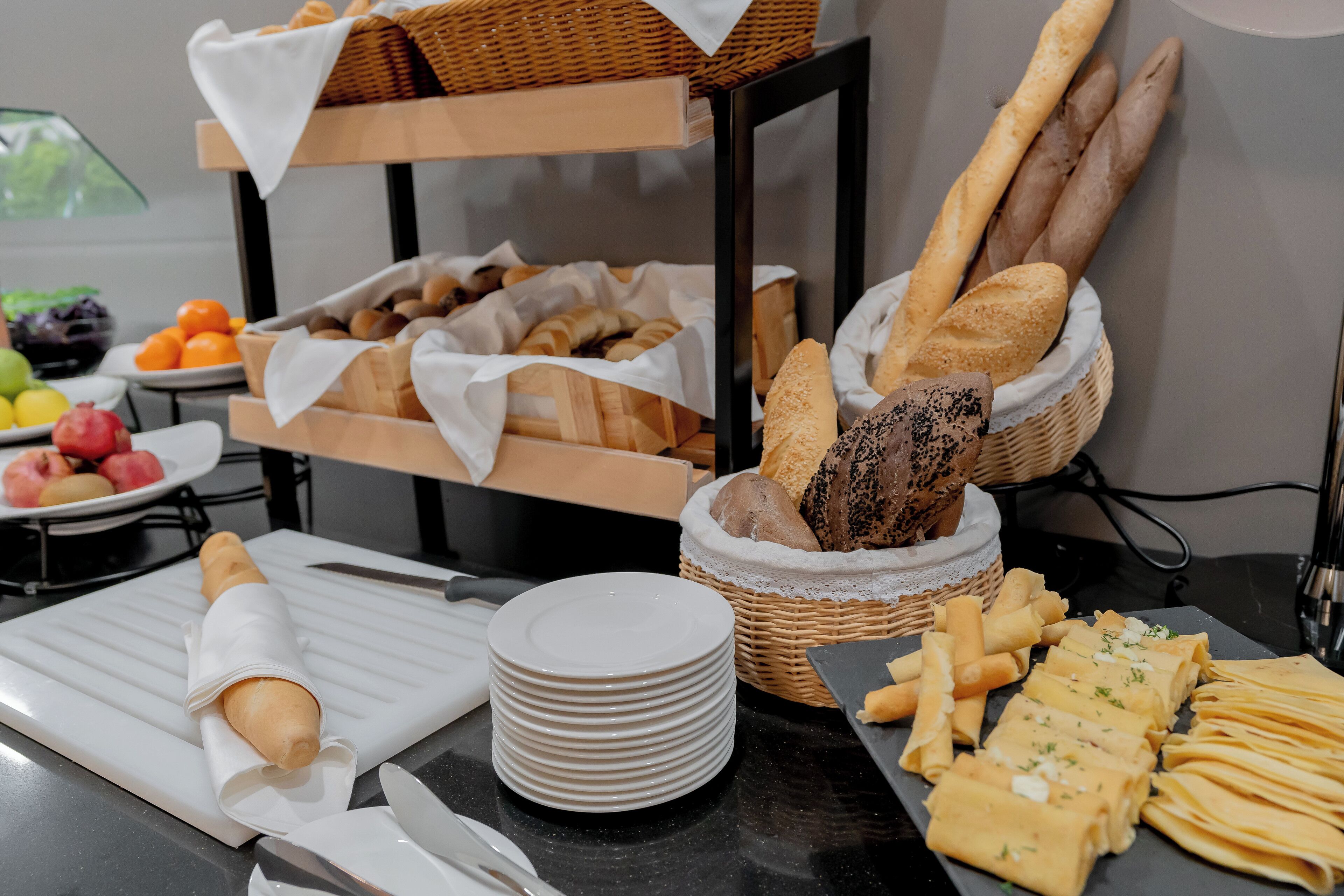 A buffet table with various breads, pastries, and fruits.