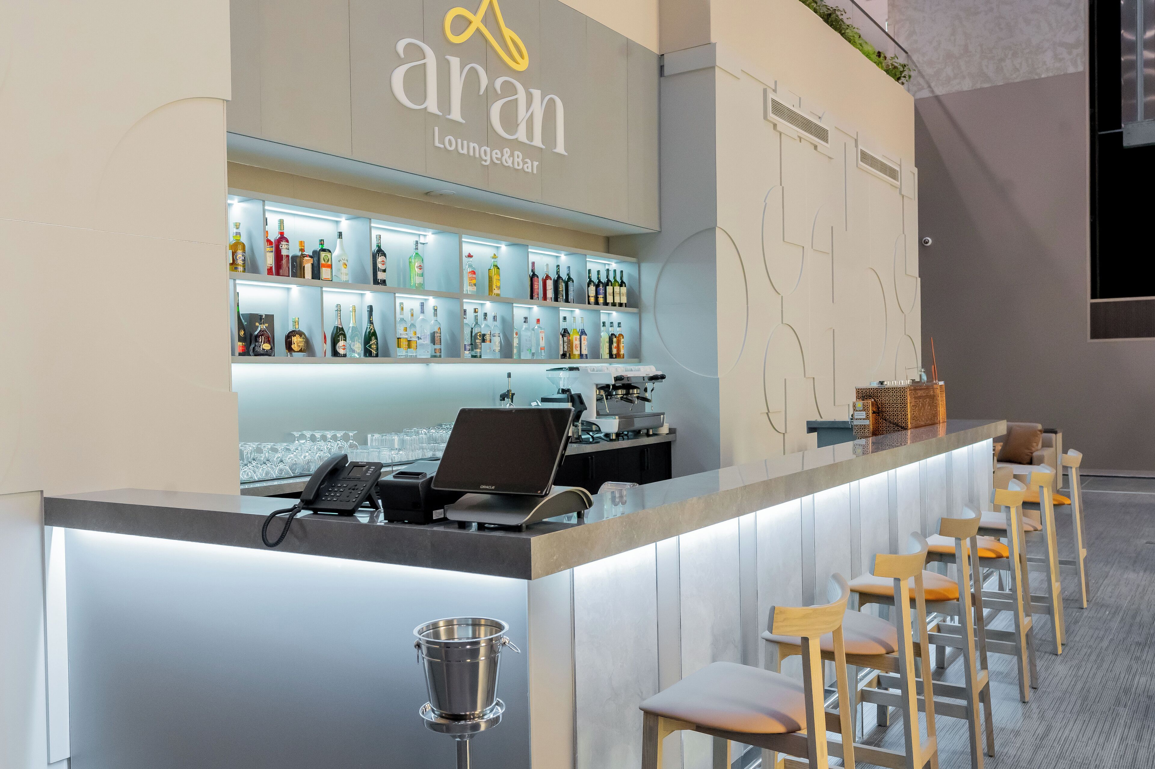 A bar area with a counter, bar stools, and a variety of bottles.