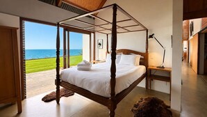 Un lit à baldaquin avec vue sur la mer, une lampe et un tapis en fourrure.