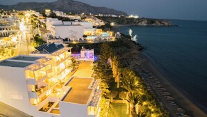 A coastal hotel with multiple floors, outdoor pool, and beachside seating. - Artemis Hotel (Makry Gialos)