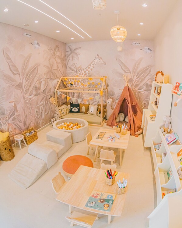 A child's playroom with a jungle theme, including a playhouse, a teepee, and animal-themed decorations.