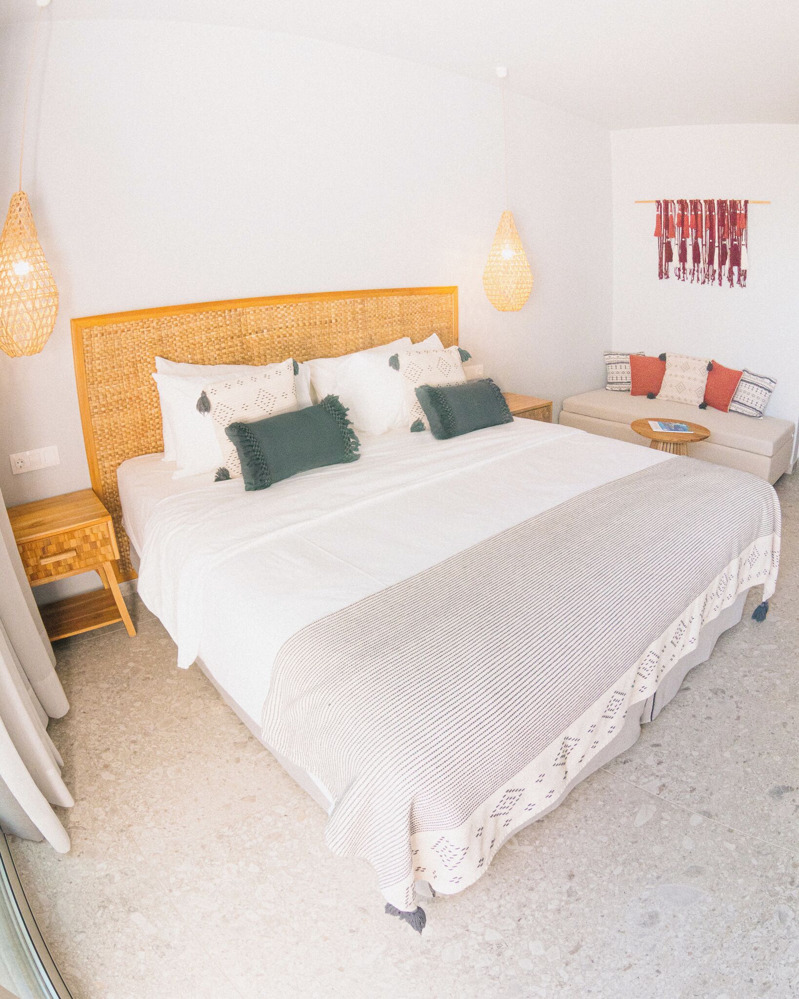 A bedroom with a large bed, two bedside tables, a small round table, and a sofa.