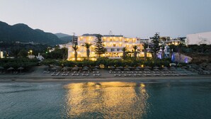 A beachfront hotel with multiple floors, a pool area, and beach umbrellas. - Artemis Hotel (Makry Gialos)