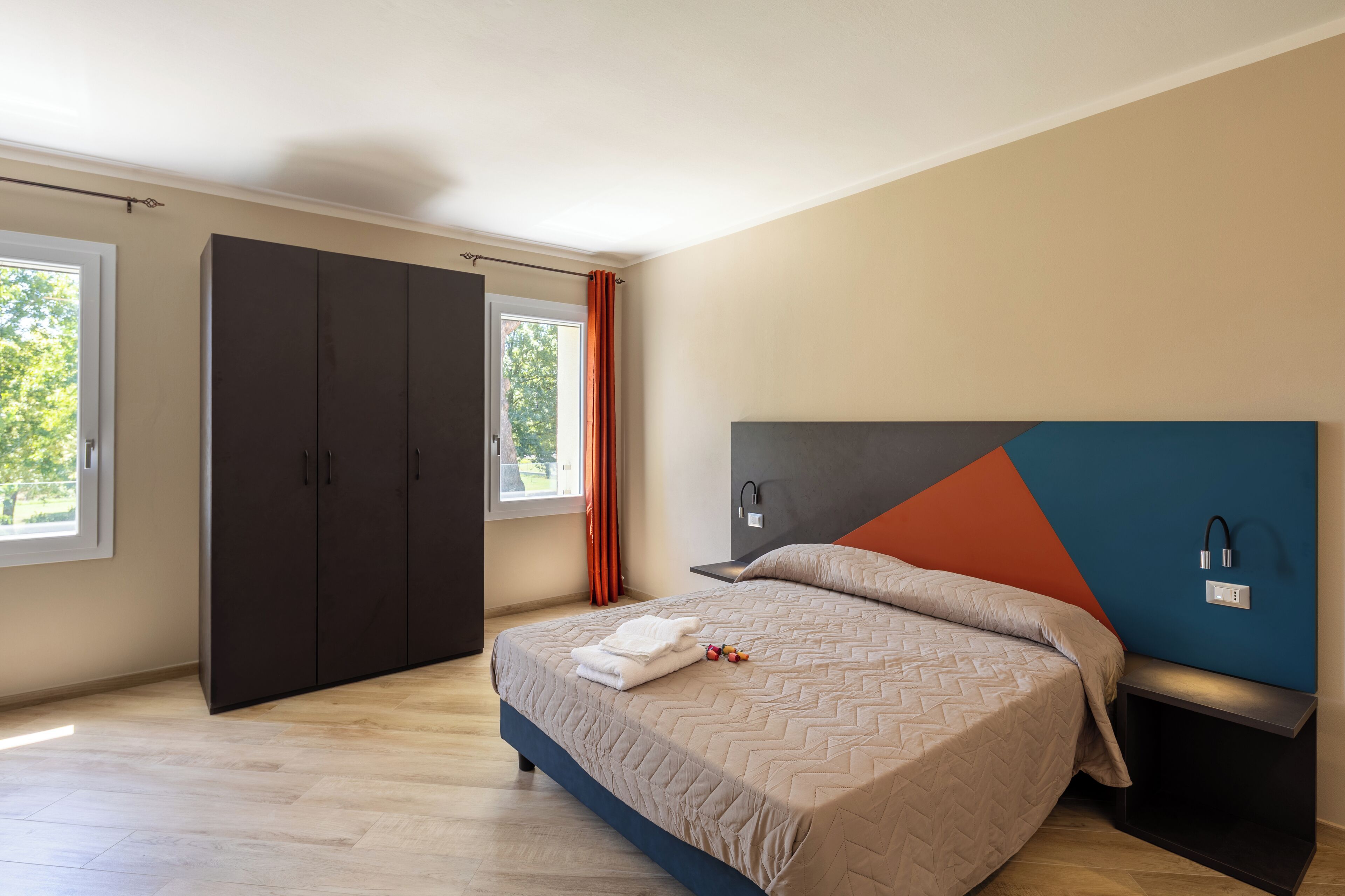 A modern bedroom with a bed, wardrobe, and bedside table.
