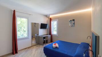 Un dormitorio con una cama, un escritorio, una silla, un televisor y una ventana.