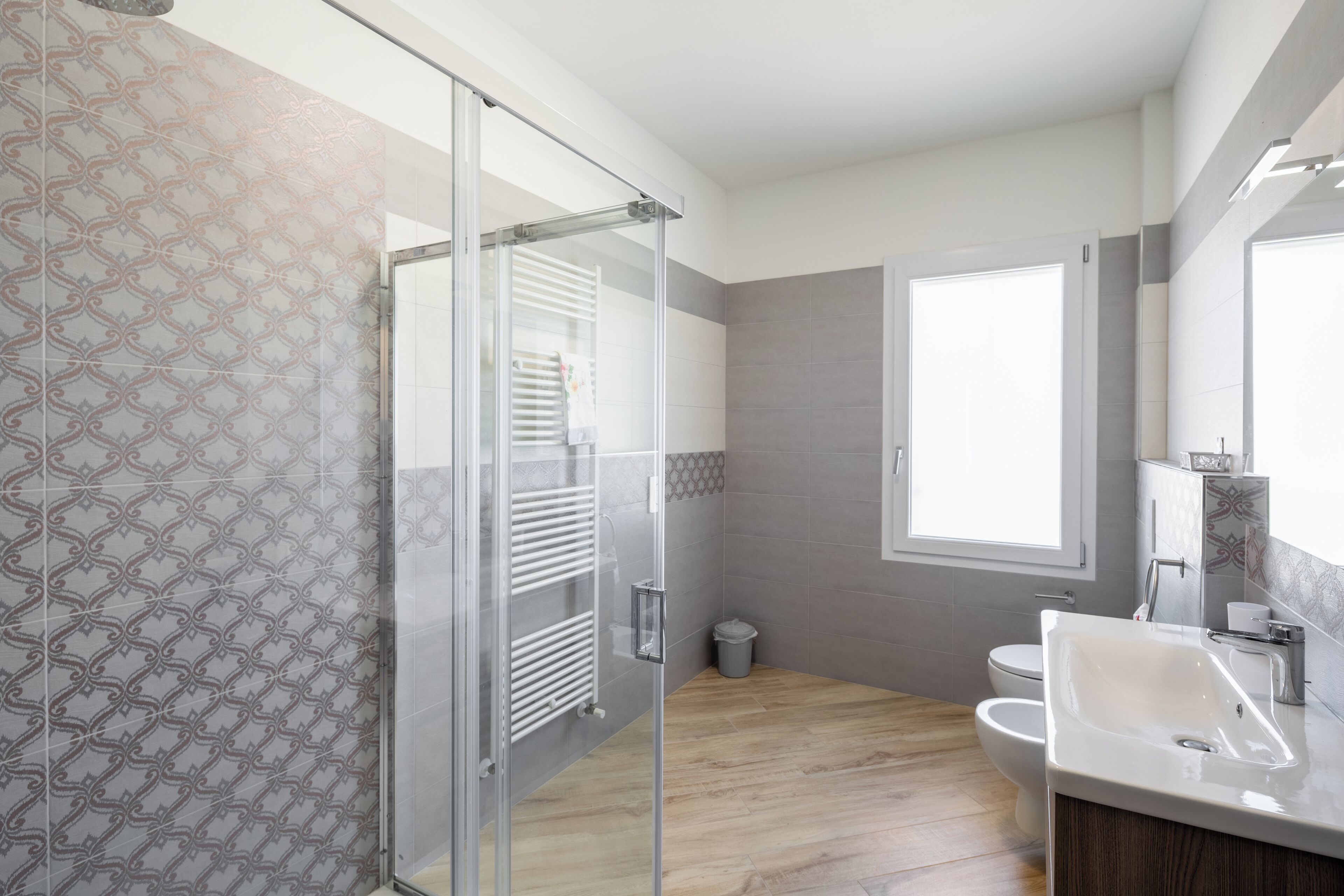 A modern bathroom with a glass shower enclosure, a toilet, and a sink with a mirror above it.