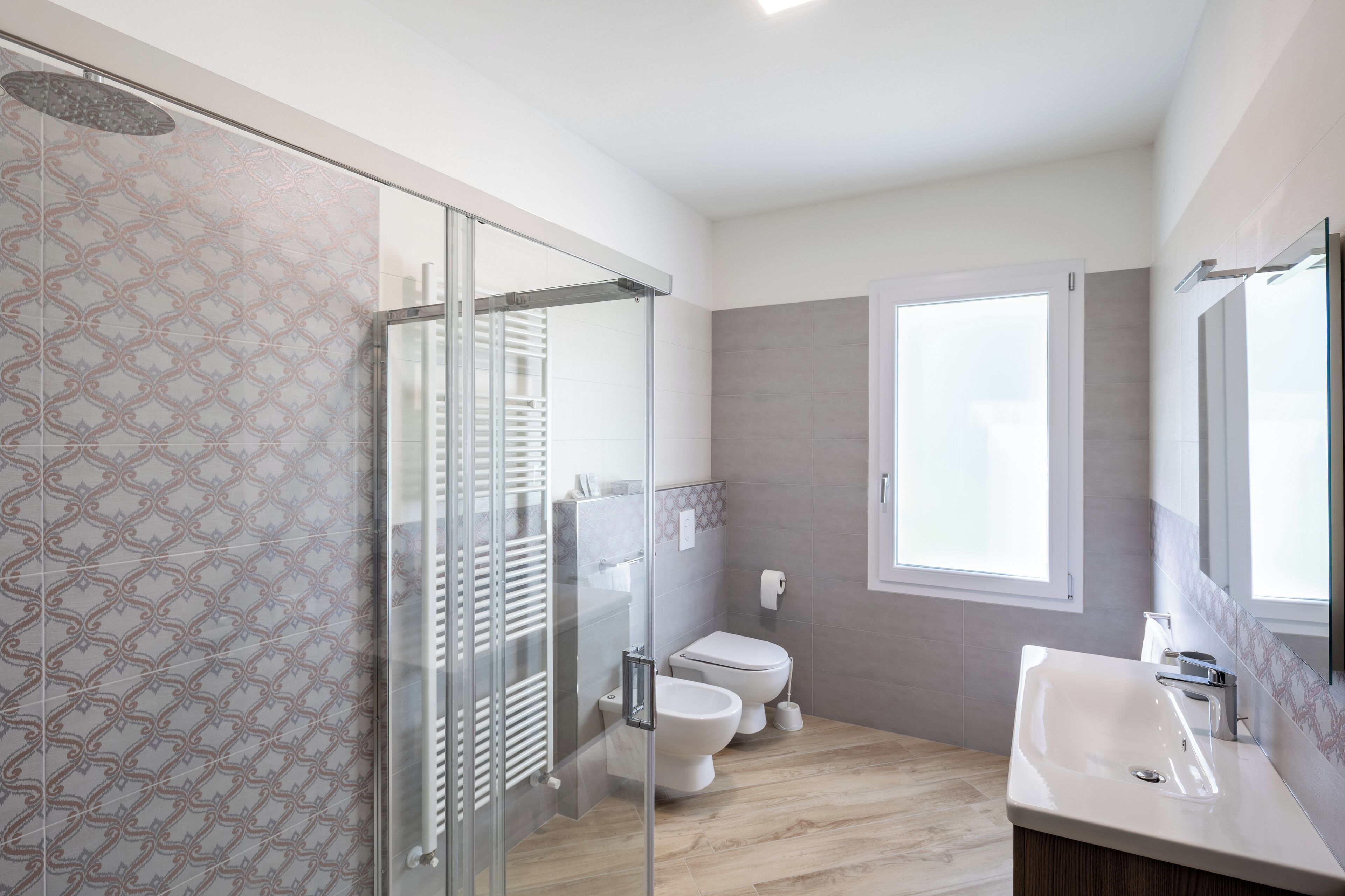 Un bany modern amb plat de dutxa de vidre, un vàter i un lavabo amb mirall.