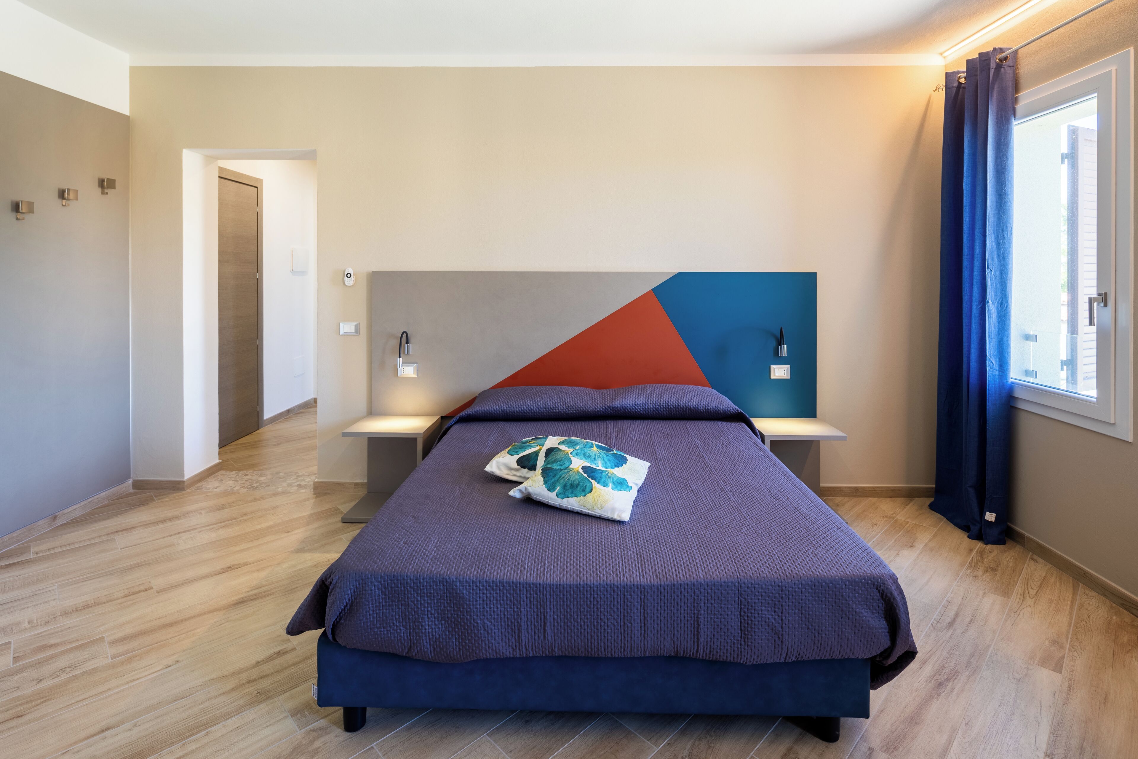 Une chambre à coucher moderne avec un lit, des tables de chevet et une fenêtre avec des rideaux.