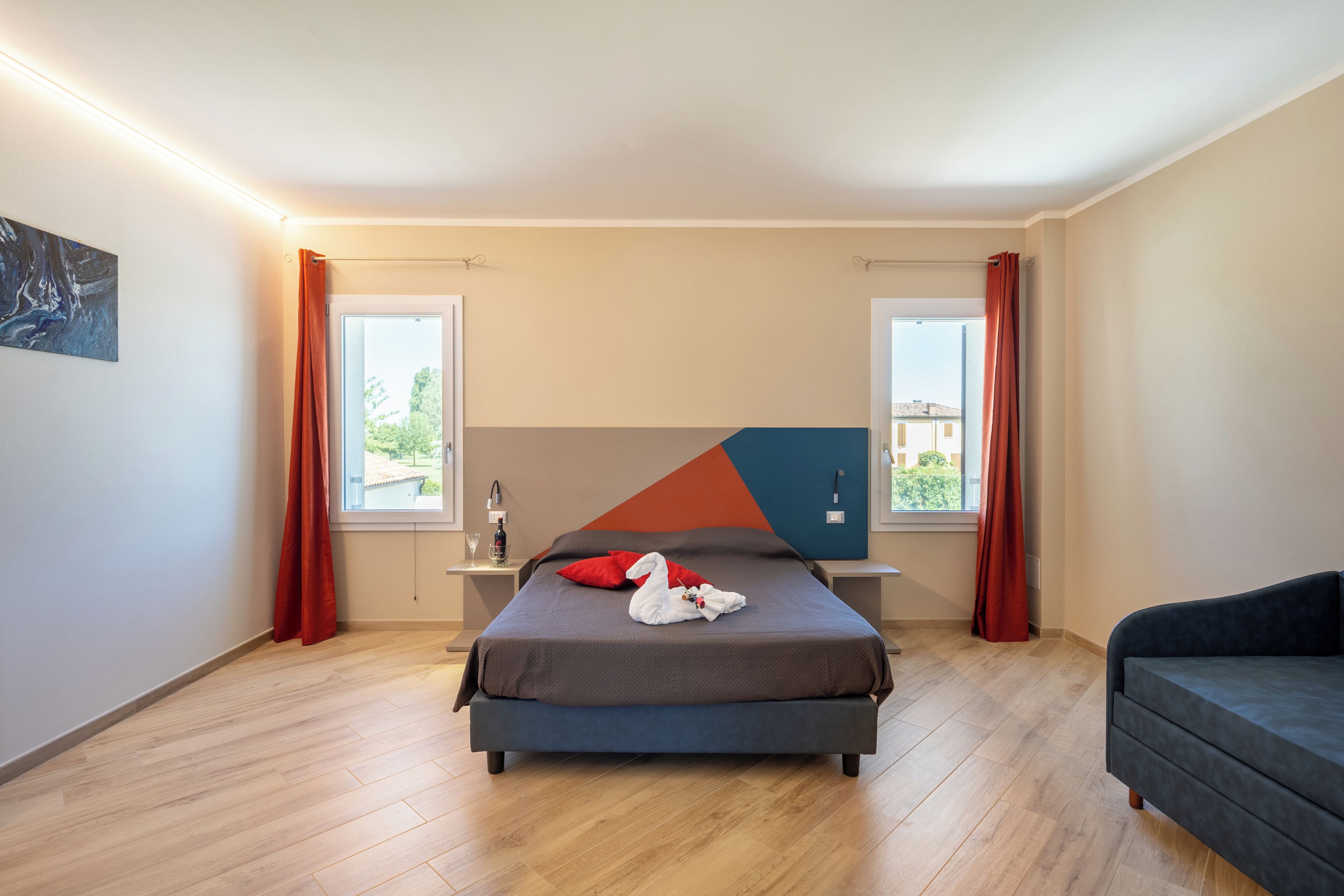 A modern bedroom with a bed, a sofa, and a large window.