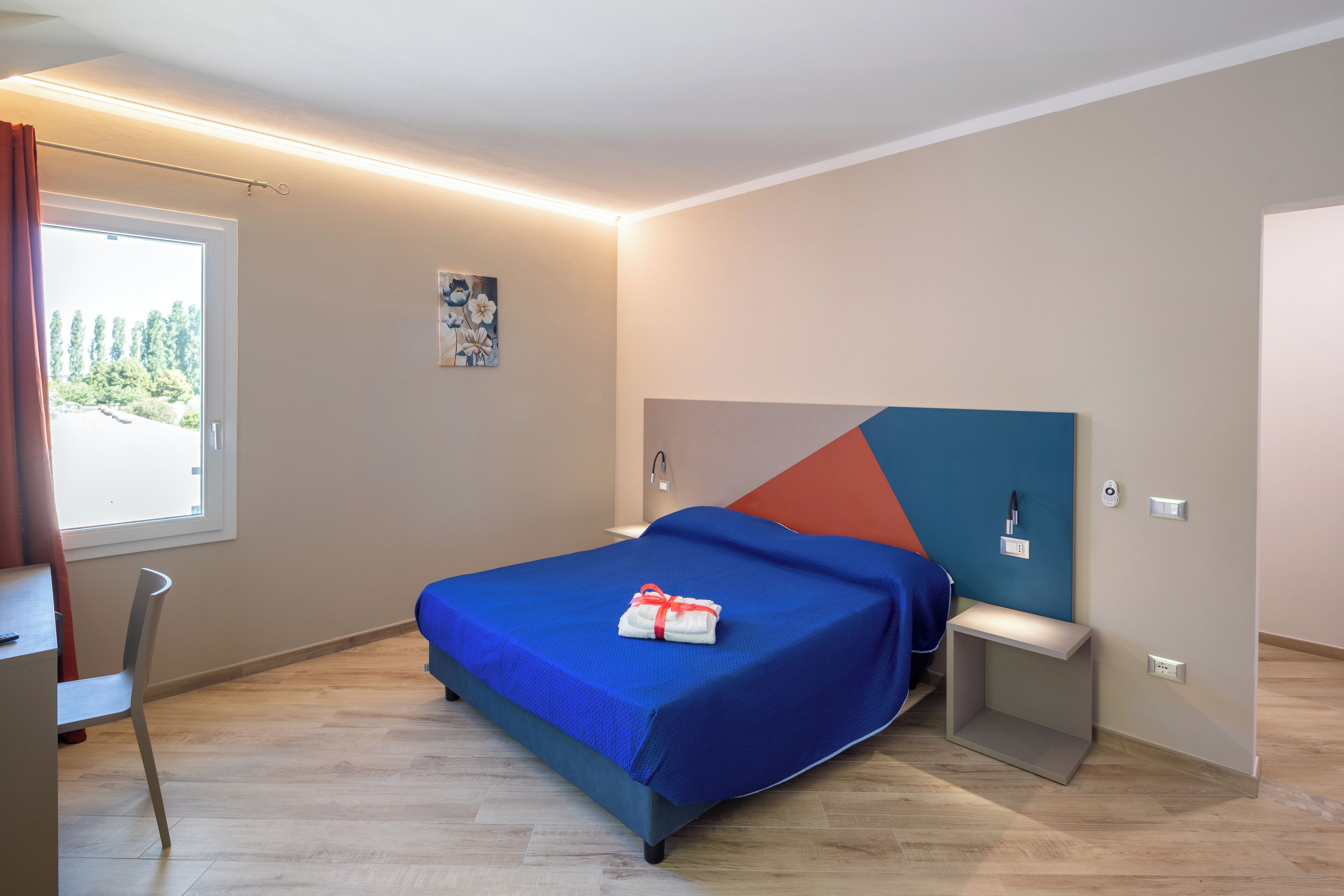 A modern hotel room with a bed, a desk, and a chair.