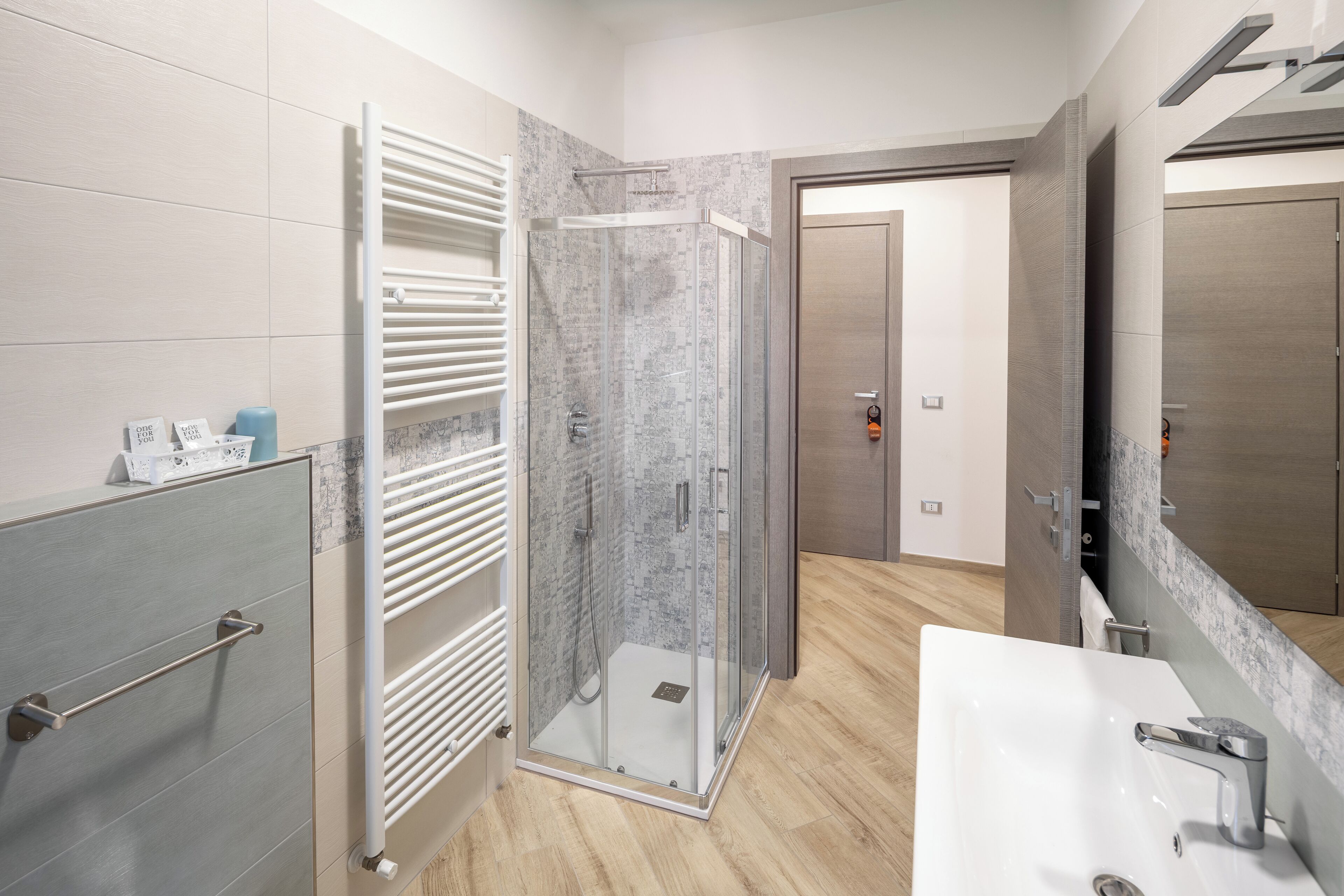 A modern bathroom with a glass shower enclosure, a white sink, and a towel rack.