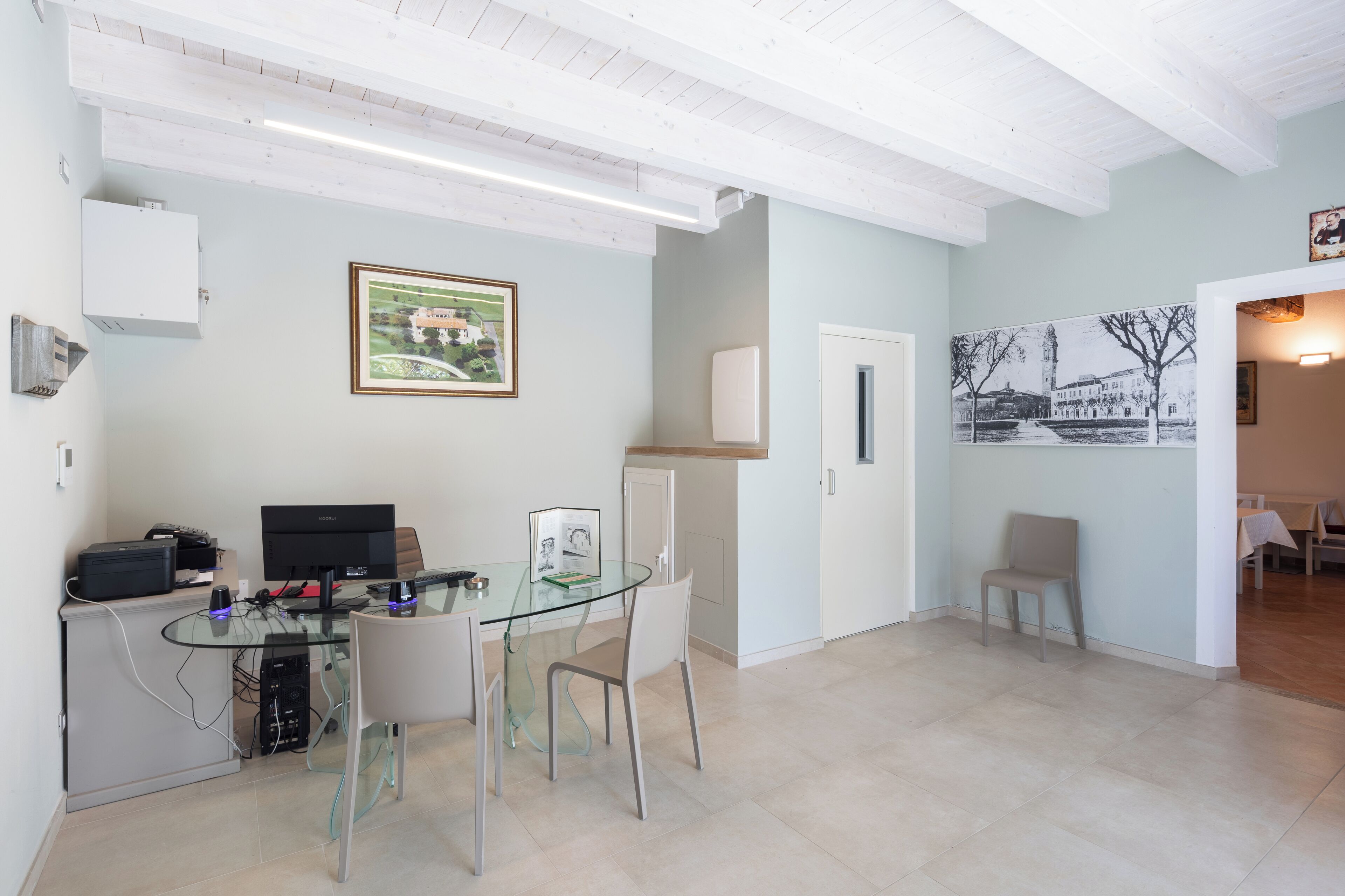 Una cocina moderna con una mesa de comedor de vidrio, armarios blancos y un cuadro en la pared.