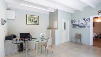 Una cocina moderna con una mesa de comedor de vidrio, armarios blancos y un cuadro en la pared.