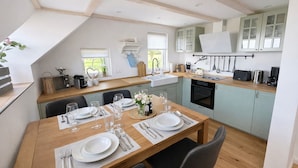 Une cuisine moderne avec un coin repas, comprenant une table en bois pour quatre personnes, un four encastré et des placards bleu clair.