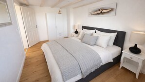 Une chambre à coucher comprenant un lit, des tables de chevet, une armoire et un miroir.