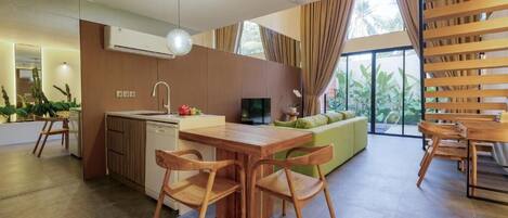 A modern kitchen with wooden cabinets, a dining area with a wooden table and chairs, and a large window with curtains.