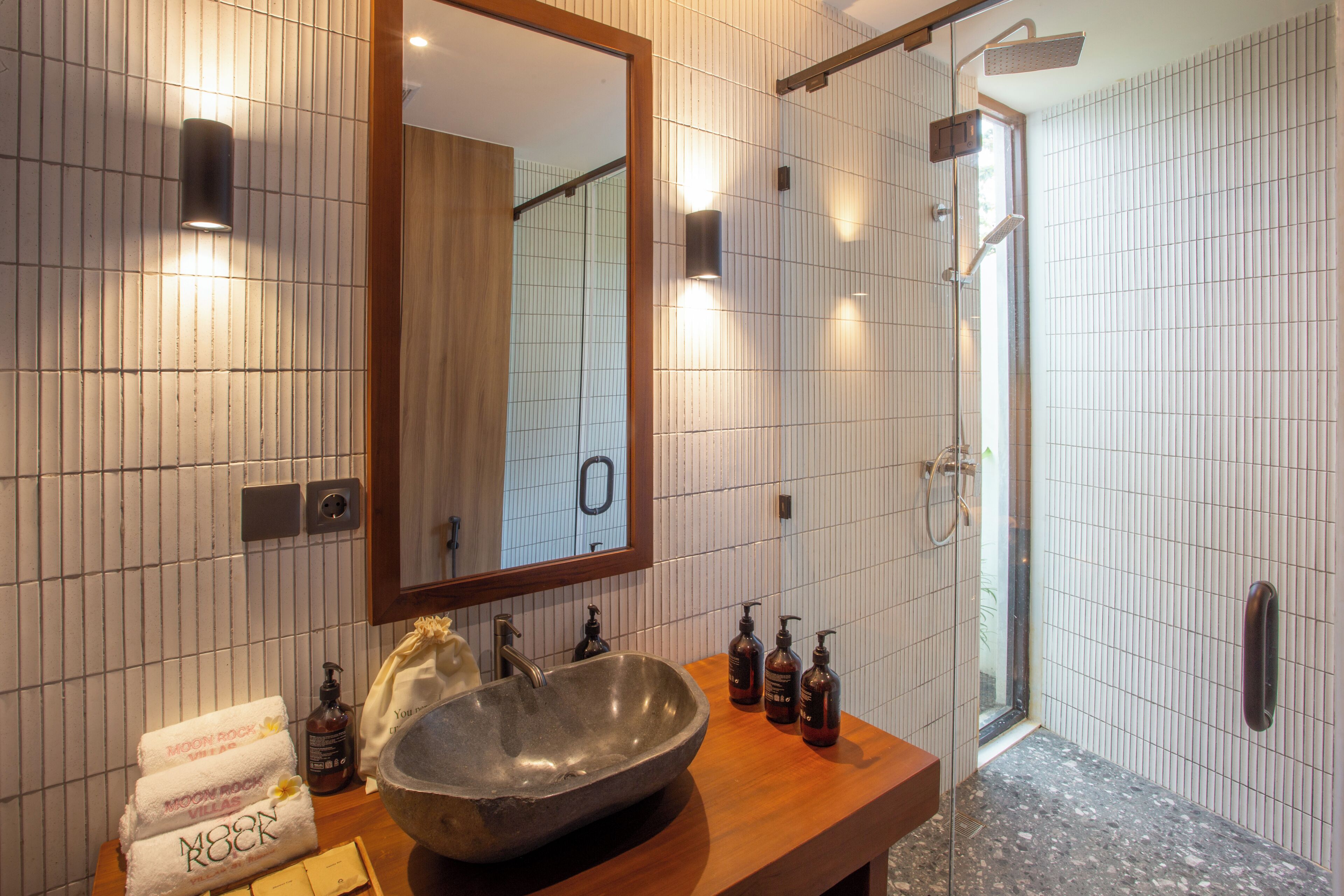Un baño con un espejo grande, un lavabo de piedra y una zona de ducha.